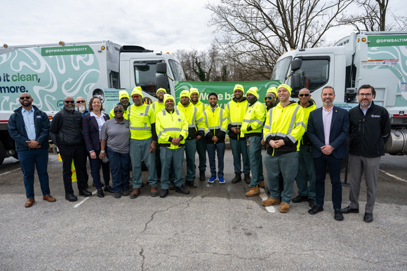 Mayor Brandon M. Scott with City staff outside by waste collection vehicles