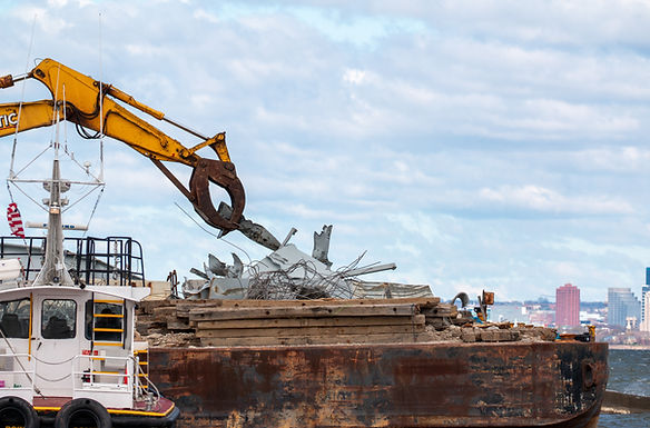 Debris removed from the Patapsco River is loaded onto a barge for removal by response personnel