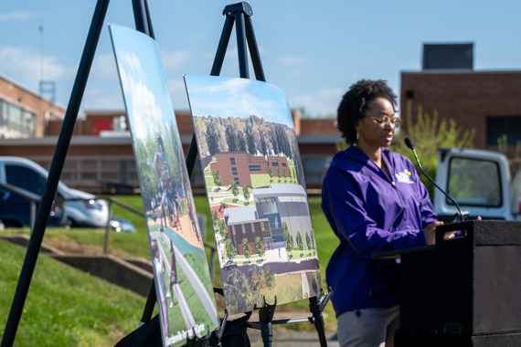 Woman speaking at podium in front of easels with artistic representations of the future rec center