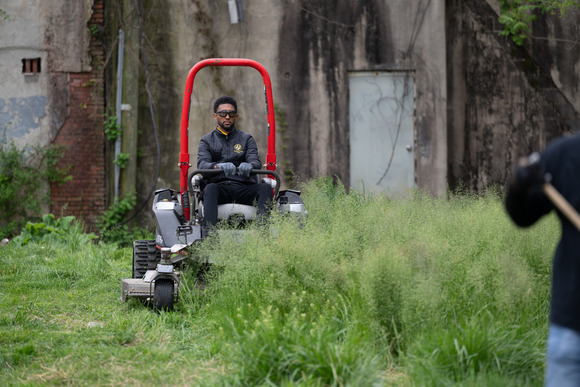 Mayor Brandon M. Scott operating a lawn mower