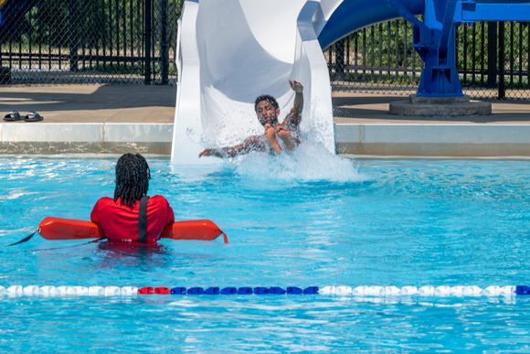 Mayor Brandon M. Scott using a water slide into a pool