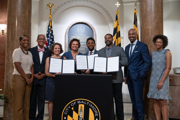 Mayor Brandon M. Scott with Council President Nick Mosby and members of the City Council at podium showing documents